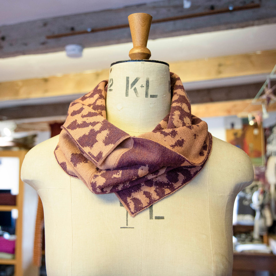 Asymmetric circle scarf in salmon and soft aubergine, in a mottled pattern on a mannequin in the Nielanell knitwear studio, Shetland.