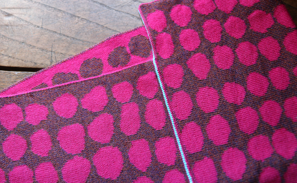 detail of a cowl loop scarf, contemporary Shetland design in irregular dots. Shocking pink and brown-purple mix with a turquoise highlight