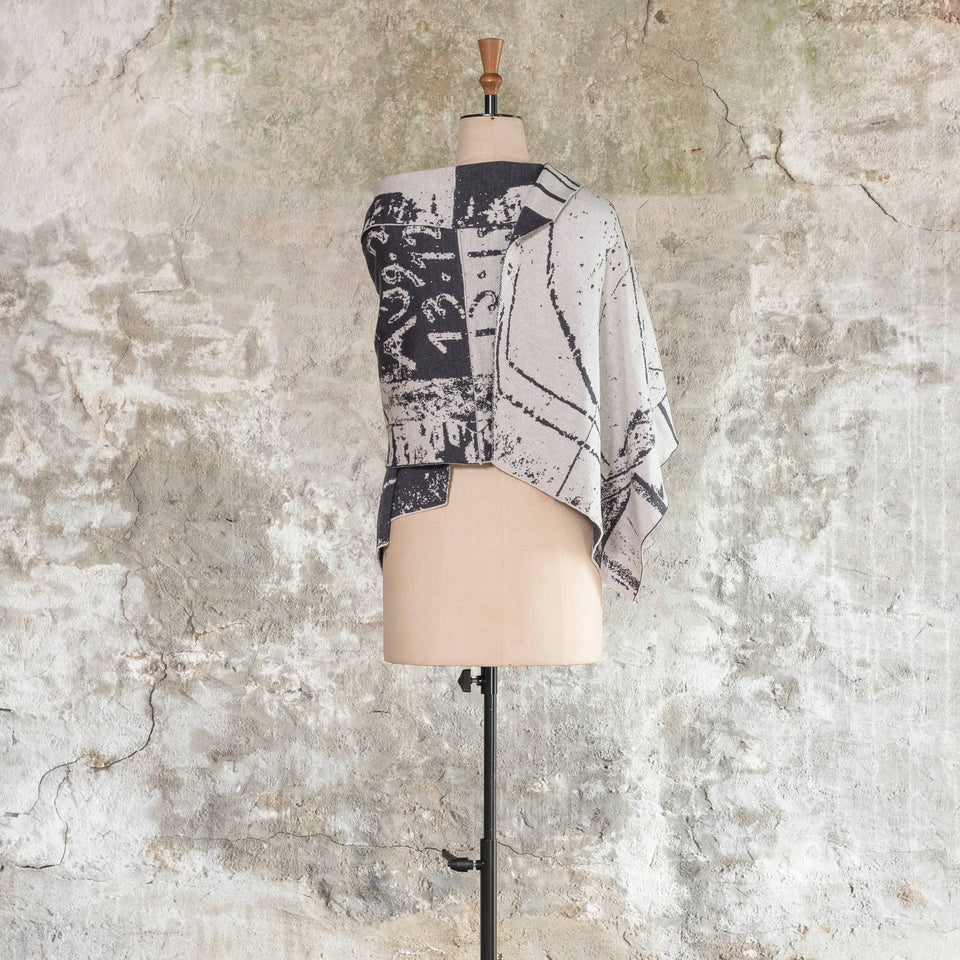 Knitted Byre wrap/shawl. Abstract, graphic design in an asymmetric shape. Shown in Charcoal and stone white