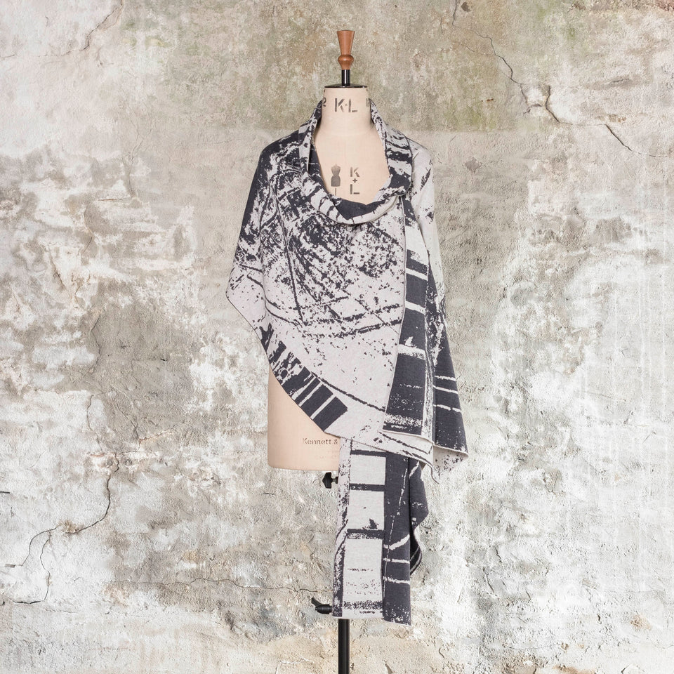 Knitted Byre wrap/shawl. Abstract, graphic design in an asymmetric shape. Shown in Charcoal and stone white
