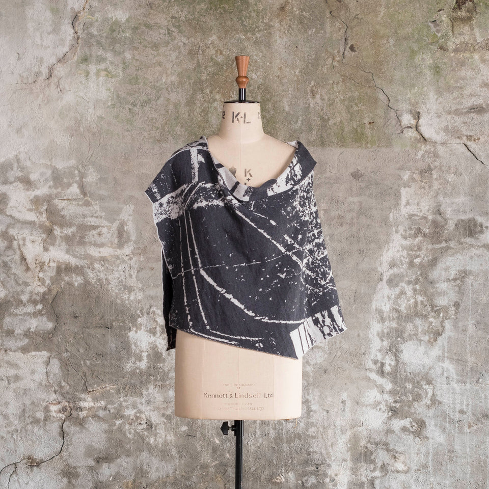 Knitted Byre capelet. Abstract, graphic design in an asymmetric shape. Shown in Charcoal and stone white