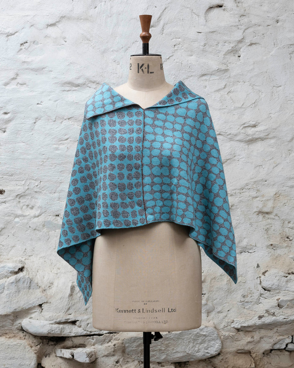 Knitted cape with an irregular dot design in two colours. Show in pale blue and marled grey