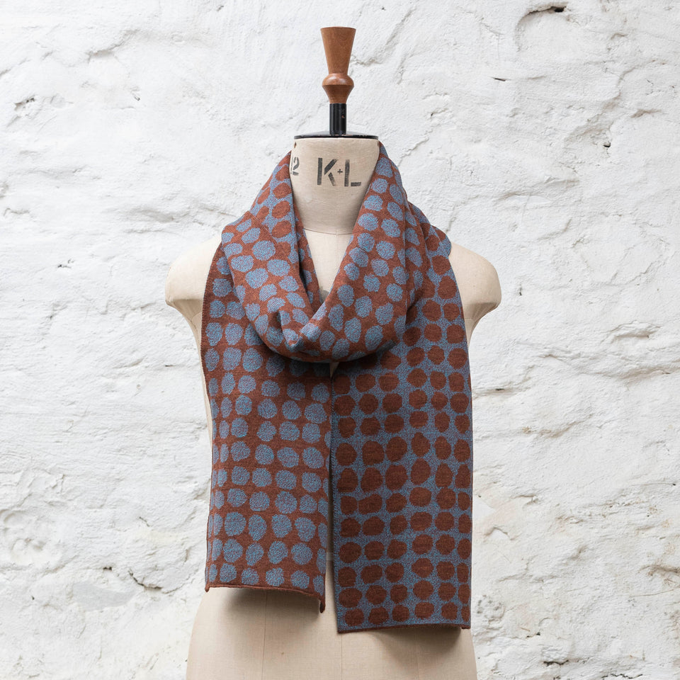 Knitted scarf with an irregular dot design in two colours. Show in dark rust and purples