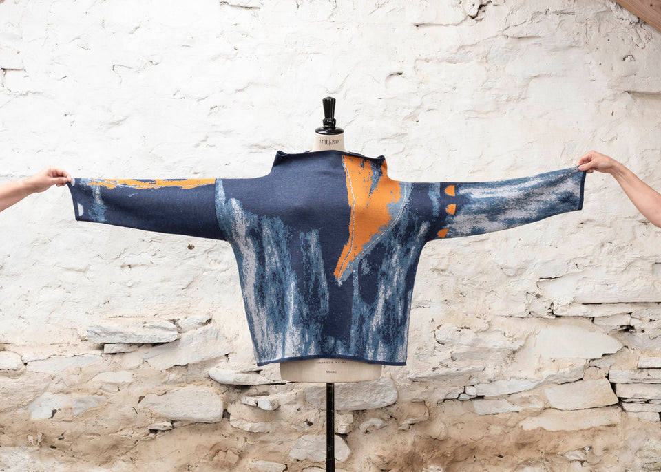 Modern Scottish statement knitwear. Wearable art, this jumper features a motif derived from drawings in Hoswick. Abstract textures in sea blues with orange highlights