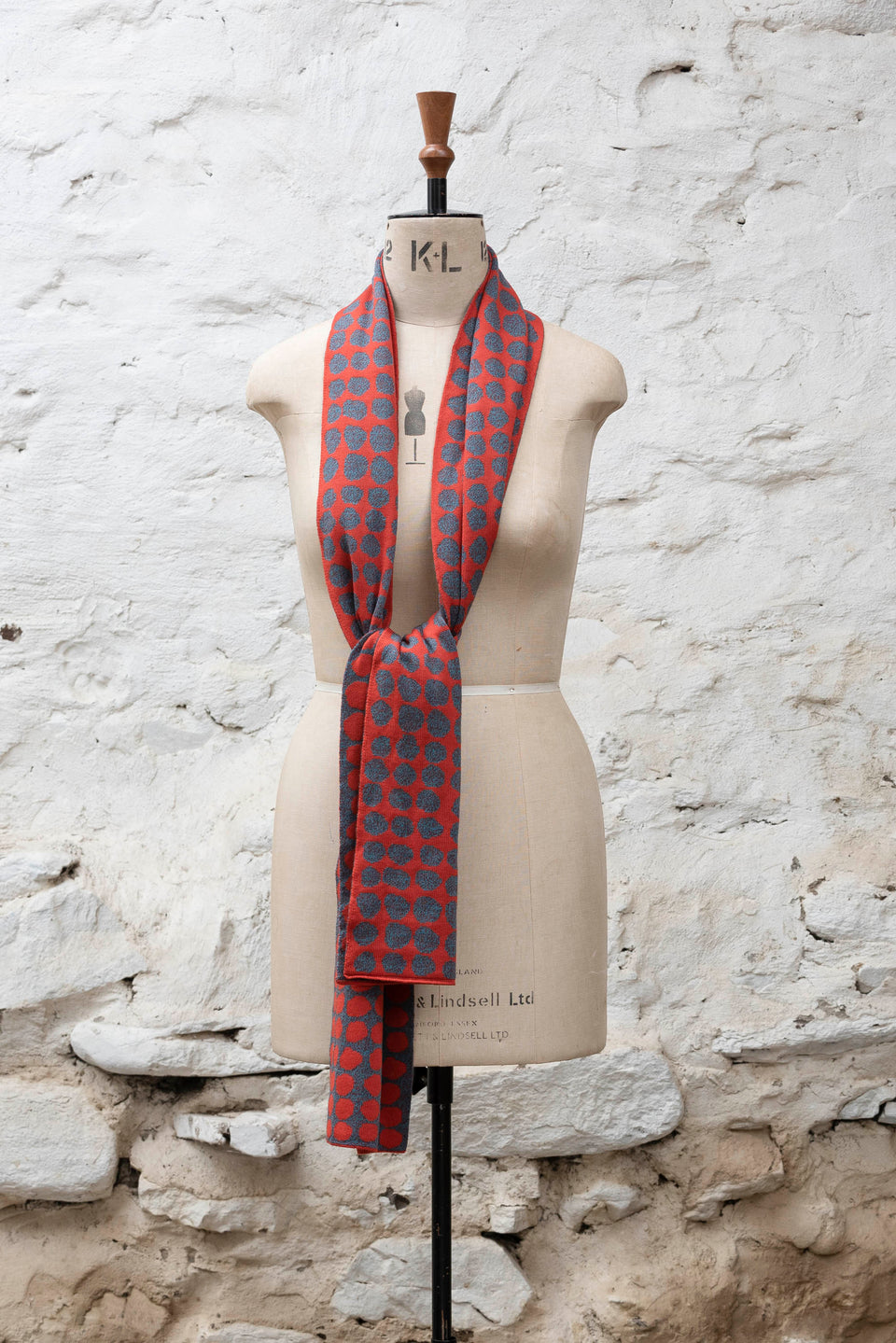 Knitted scarf with an irregular dot design in two colours. Show in dark coral and greys