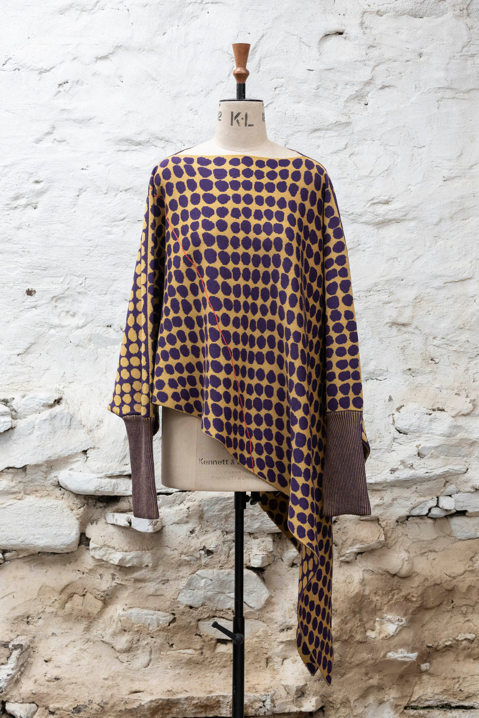 knitted asymmetric jumper with an irregular dot pattern. Shown in gold and aubergine