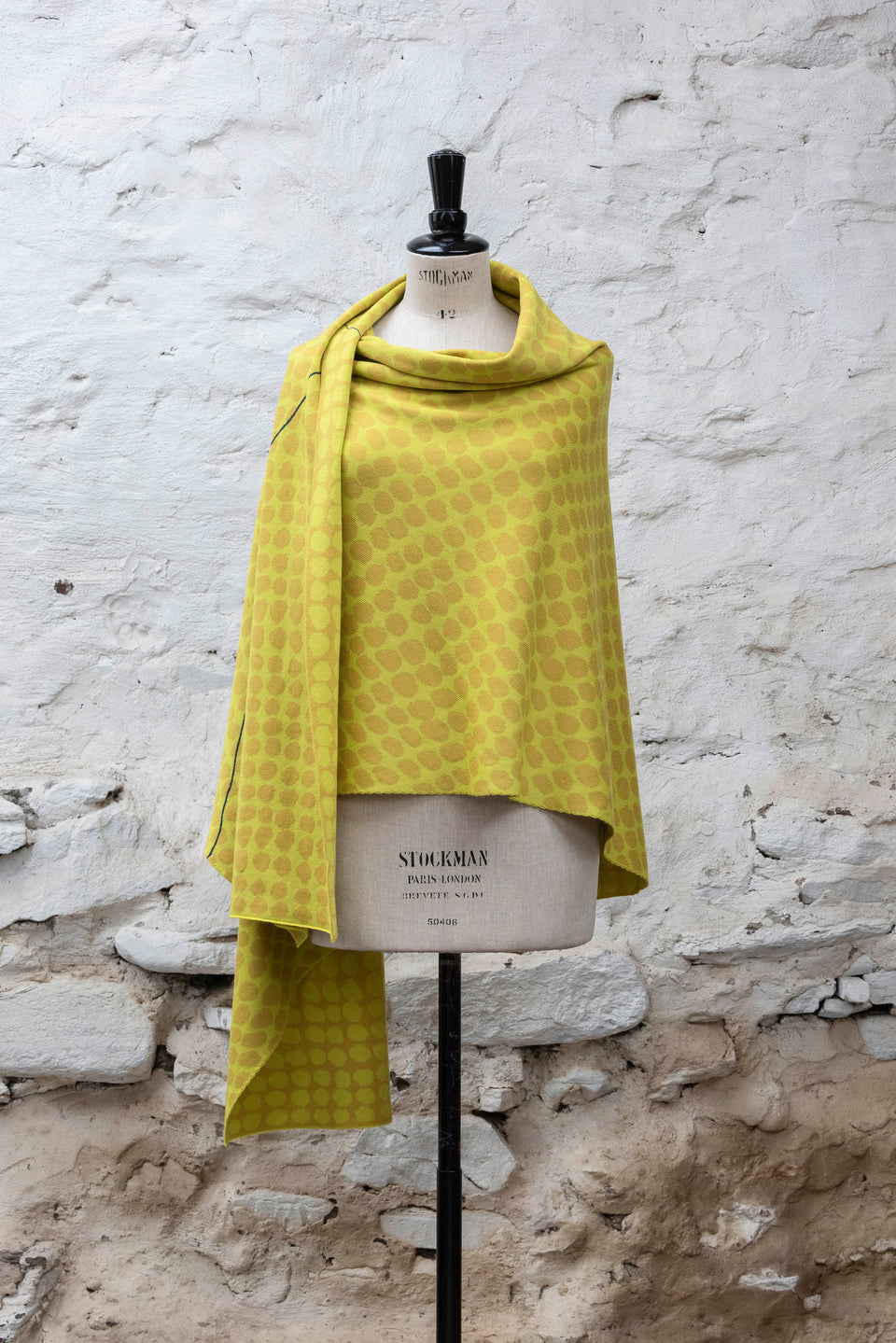 Knitted ebb-stanes wrap with irregular dot pattern shown in golds