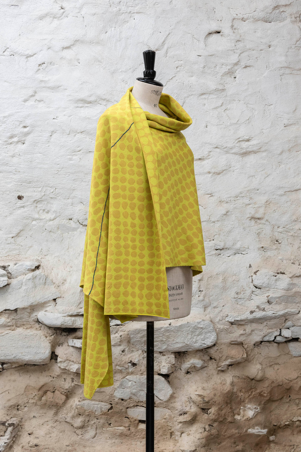 Knitted ebb-stanes wrap with irregular dot pattern shown in golds
