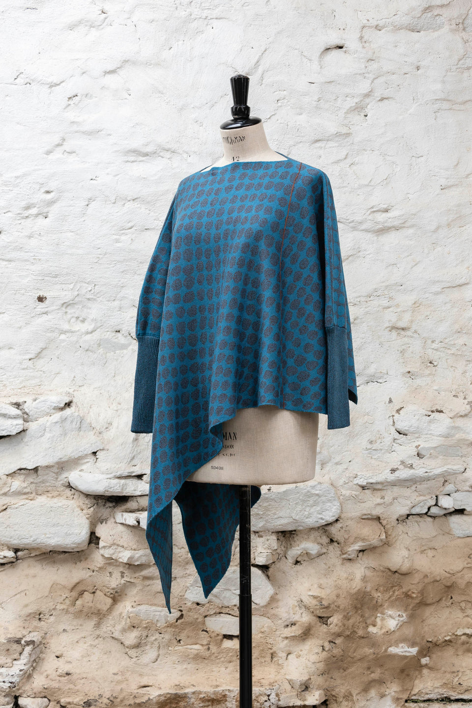 knitted asymmetric jumper with an irregular dot pattern. Shown in blues