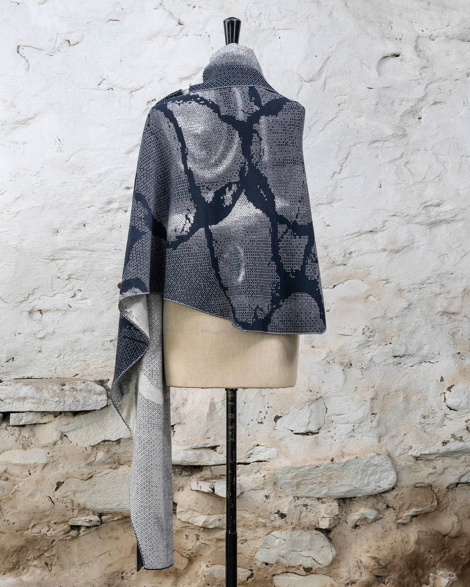 Knitted Rani shawl / wrap. Small abstract patterns make up a larger design with photographic imagery. Shown in inky blue and antique white