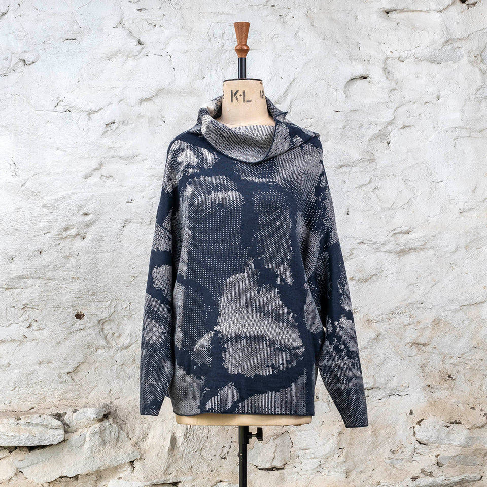 Knitted Rani jumper. Small abstract patterns make up a larger design with photographic imagery. Shown in inky blue and antique white
