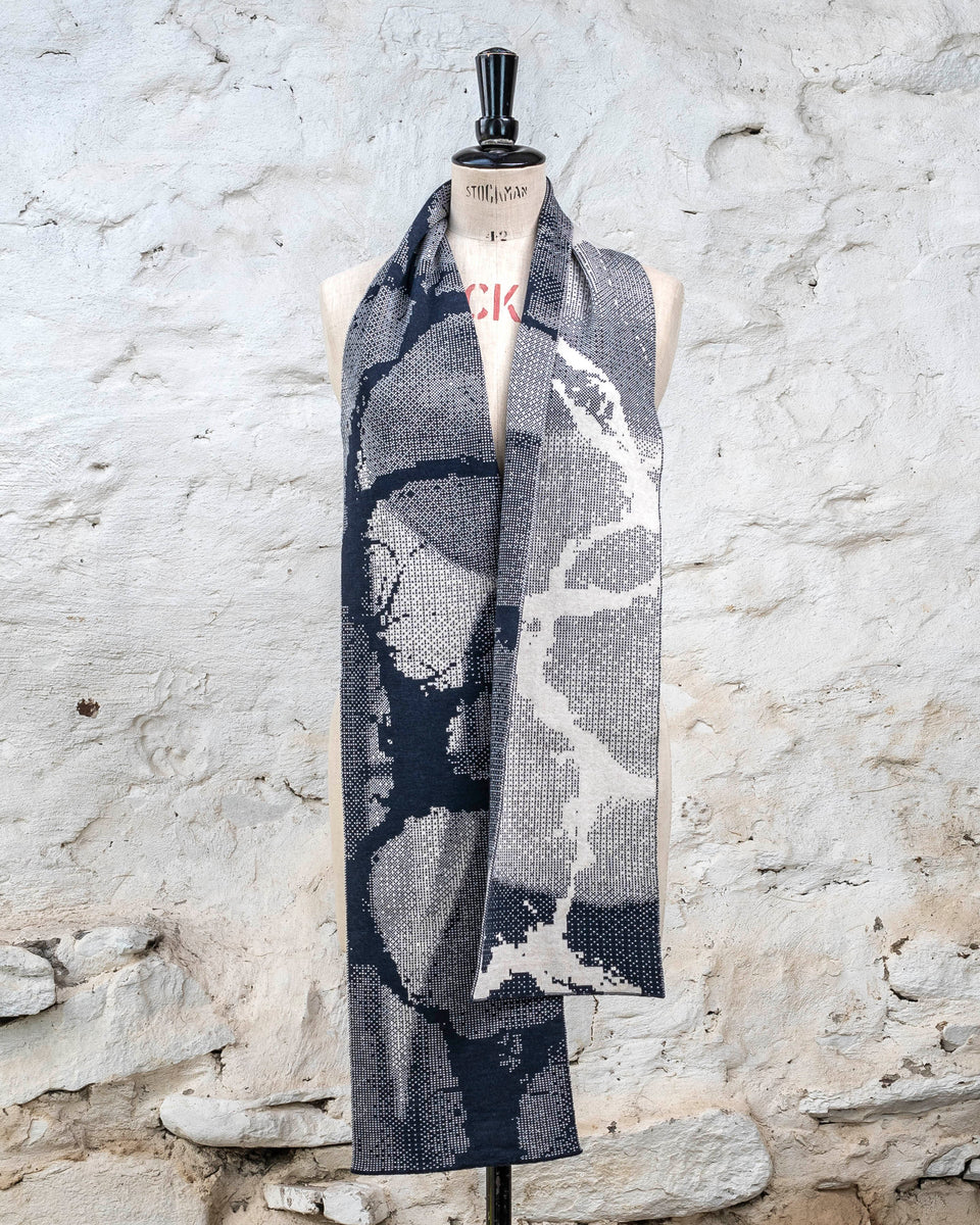 Knitted Rani scarf. Small abstract patterns make up a larger design with photographic imagery. Shown in inky blue and antique white