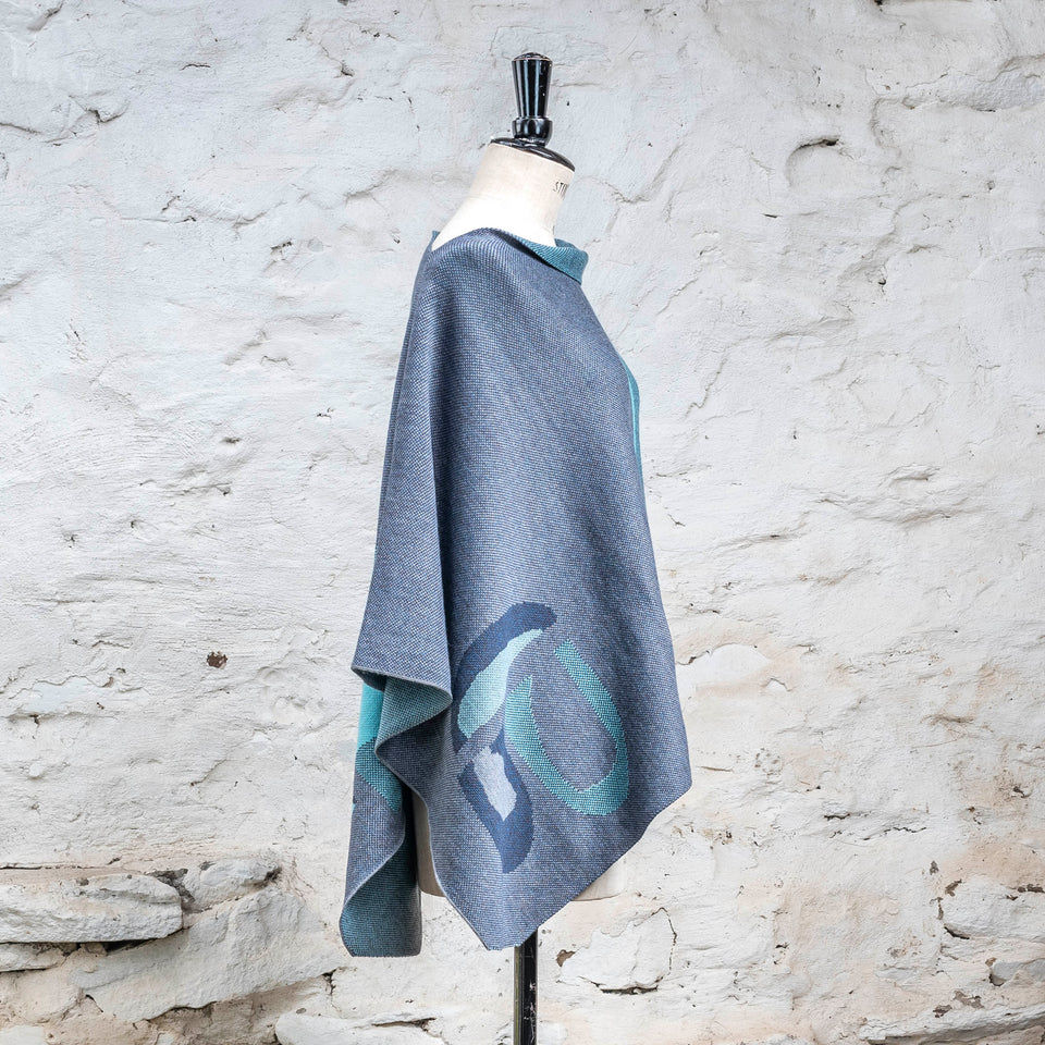 Knitted cape in blues with accents in aqua. The pattern is abstract
