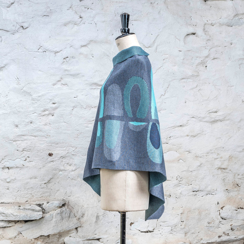 Knitted cape in blues with accents in aqua. The pattern is abstract