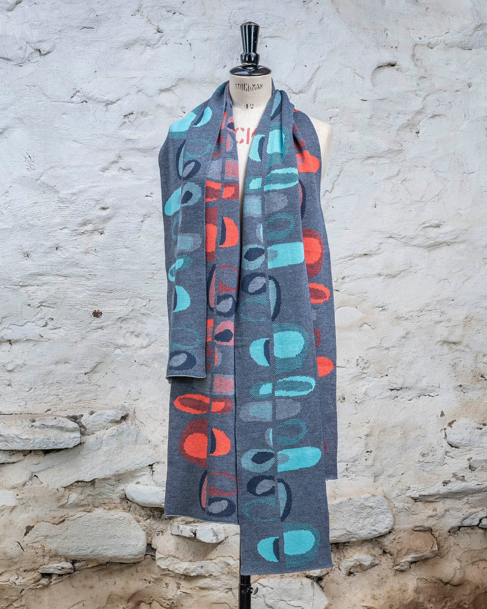 Knitted scarf in blues with accents in aqua or coral. The pattern is abstract