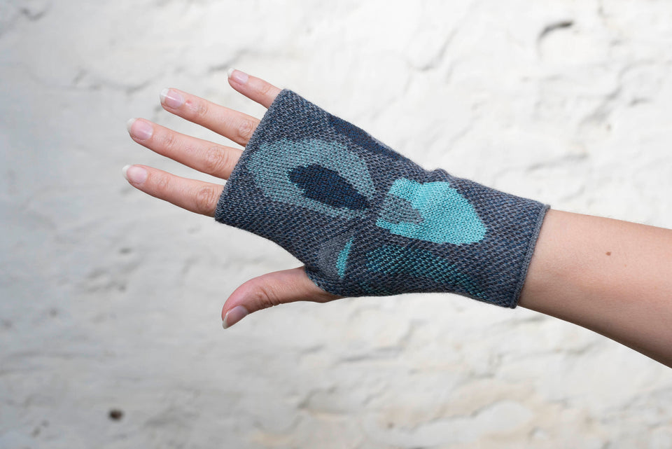 Knitted gauntlet mitts in blues with accents in aqua. The pattern is abstract
