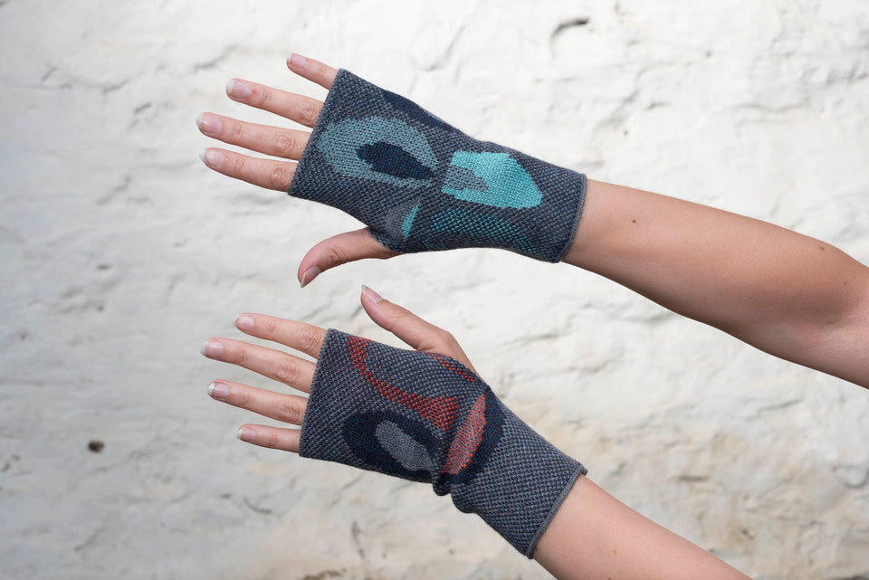 Knitted gauntlet mitts in blues with accents in coral or aqua. The pattern is abstract