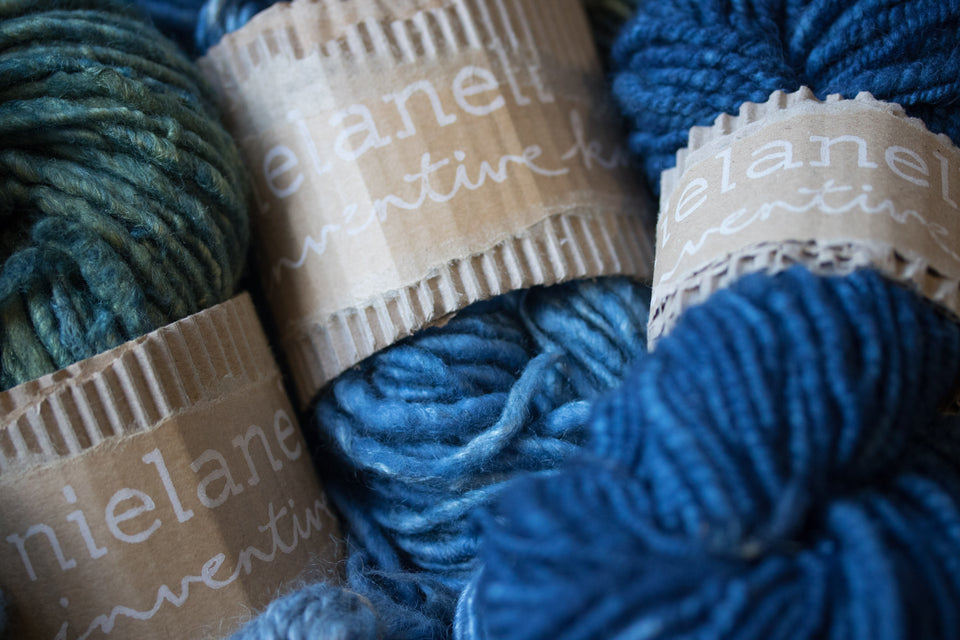 three hand-dyed and handspun skeins of yarn, dyed with natural indigo. shown with yarn bands.