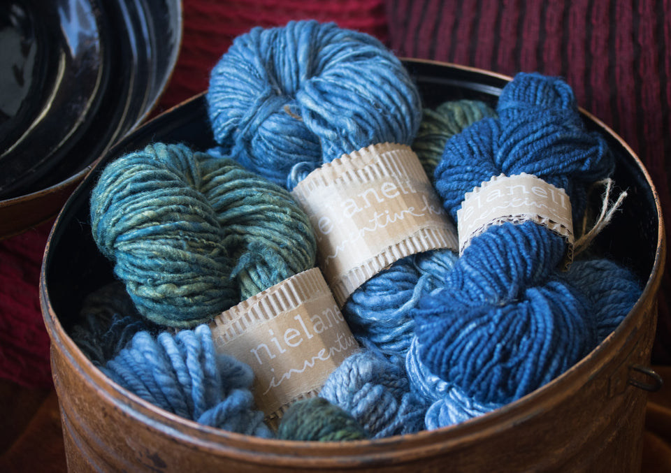 selection of art yarn in natural indigo, displayed in a tin