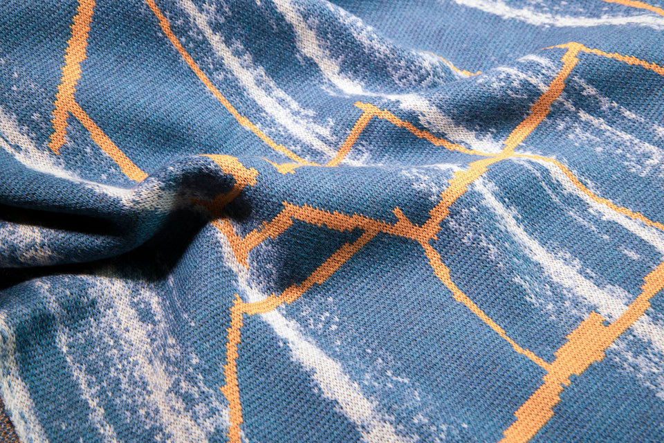 closeup up finely knitted Hoswick Paint cape - sea blues with linear orange highlight  design