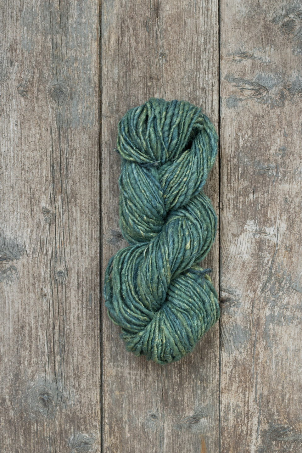 handspun, hand-dyed indigo art yarn. shetland wool, linen, tussah silk shown wound in a skein
