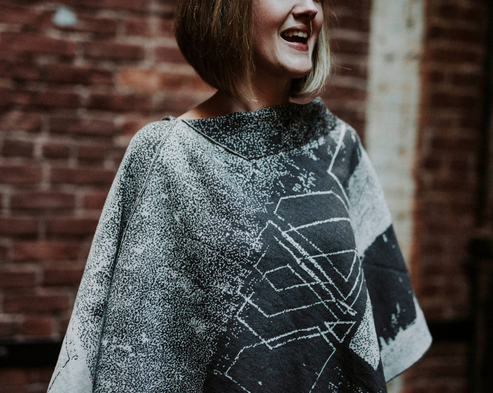 Knitted Byre cape. Wearable art, a piece of Scottish knitwear in an Abstract, graphic design in an asymmetric shape. Shown in Charcoal and stone white